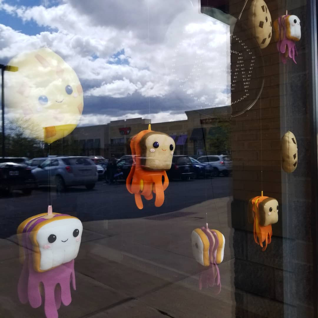 Silly sandwich and cookie plush art in a window installation by Sophia Adalaine at Matty J's Bakery and Cafe