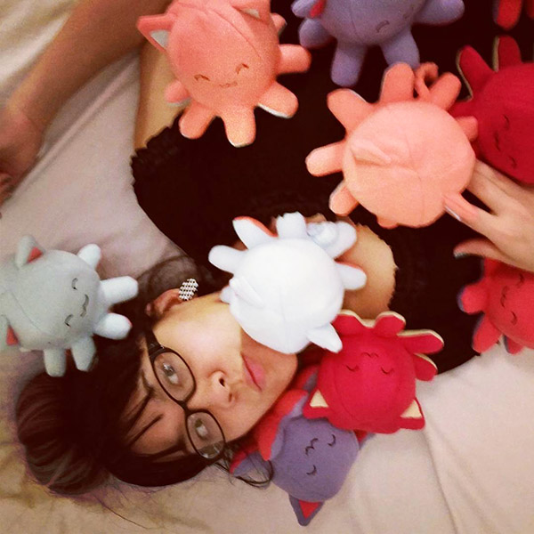 Sophia the creator of Taneko has a small mound of Taneko the Octo-puss plush toys sitting on her