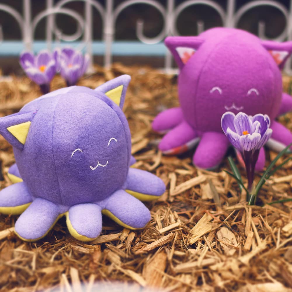 2 Tanekos sitting in a garden bed with purple crocuses