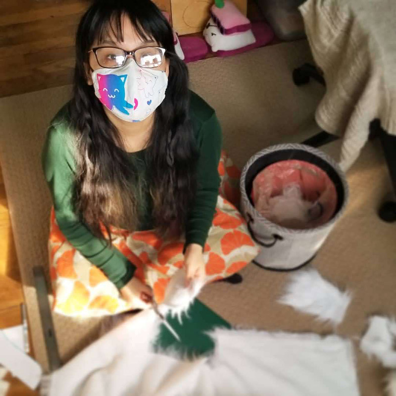 girl sitting on floor with Taneko face mask cutting faux fur fabric