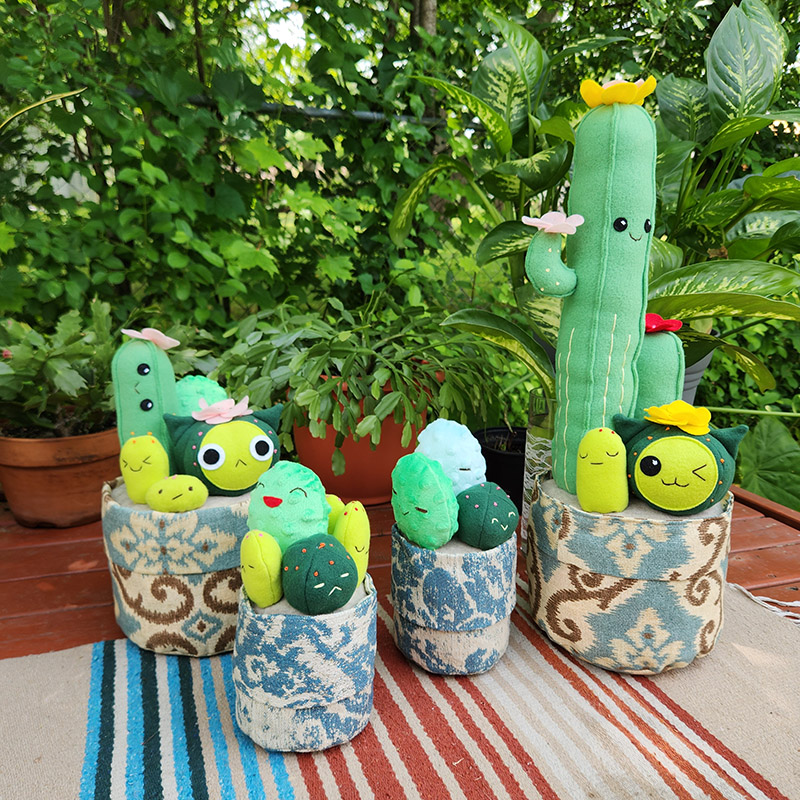 4 plush cactus pots sitting outside with house plants