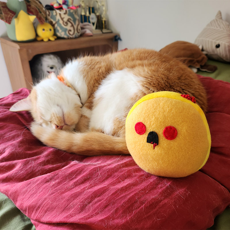 sleeping orange and white cat with Undead Jelly Donut plush toy
